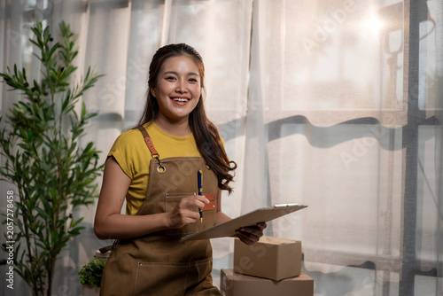 Asian woman entrepreneur smiling preparing boxes for delivery