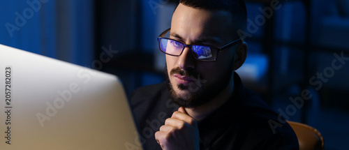 Male trader with eyeglasses working in office at night
