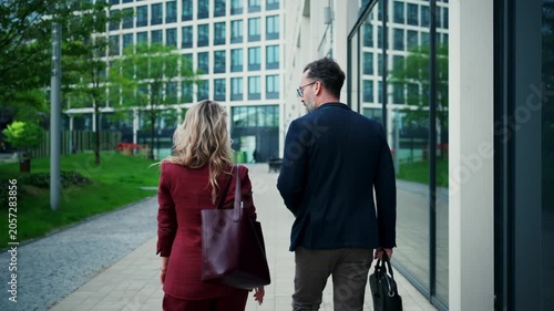 Business colleagues talking outside modern office building.