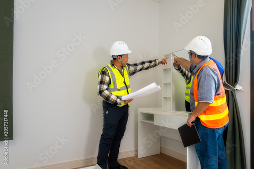 Inspecting Built-in Furniture for Room Acceptance: Engineers meticulously checking a vanity table in a new room, symbolizing fixture quality control, interior design completion and project handover.