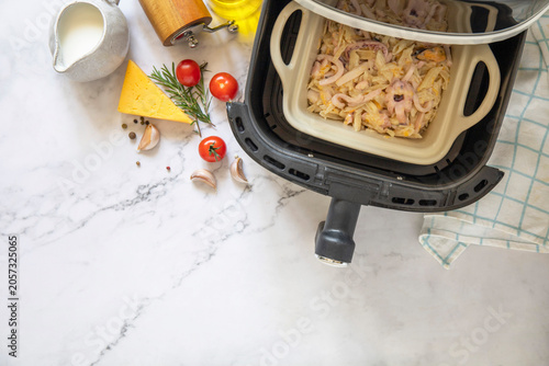 Schilderij op canvas Pasta with seafood in creamy cheese sauce, in kitchen gadget modern white air fryer