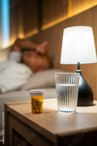Fotografie Young man may take medication before bed to treat illnesses, or take vitamins and supplements for good health and restful sleep