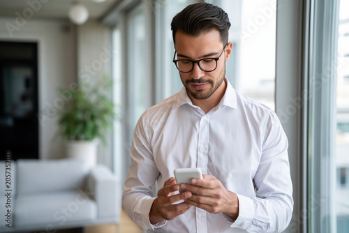 Young professional using AI assistant on smartphone in modern home office.
