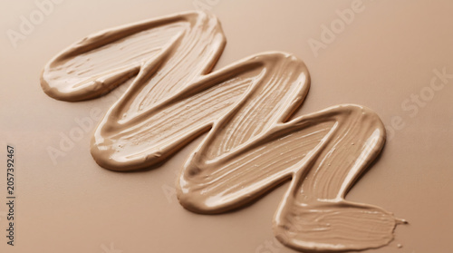 Creamy liquid makeup foundation stroke texture swiped on a smooth beige skin tone background