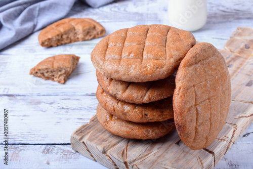 Stack of round brown rye flatbread on the light wooden background. Close-up. Country baking