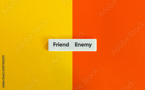 Fényképezés Friend enemy text white block split yellow orange background concept representin