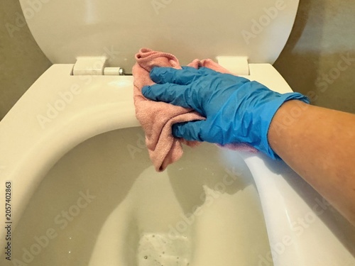 Foto A close-up of a hand in a blue glove carefully cleaning the snow-white surface of a toilet