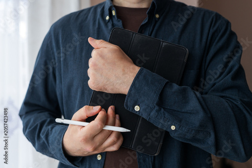 Bilde på lerret Man holding a tablet with stylus and folio case for digital device mockup backgr