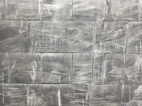 Full frame of abstract dark grey stone tile wall texture. Weathered brick pattern background surface with white paint brush strokes and grunge details.