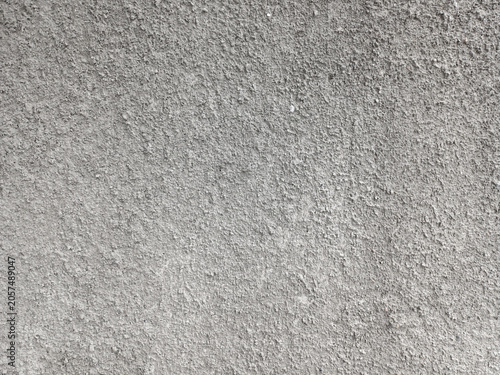 Full frame of rough grey cement wall texture. Abstract concrete background surface with grain, sand, scratches, and weathered uneven construction detail.
