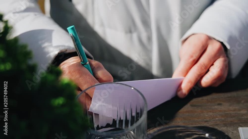 A man writes a note with a felt-tip pen on a piece of paper. Close-up shooting