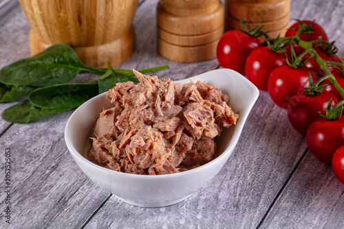 Foto Canned tuna chunks in white bowl with fresh tomatoes and spinach on wooden table