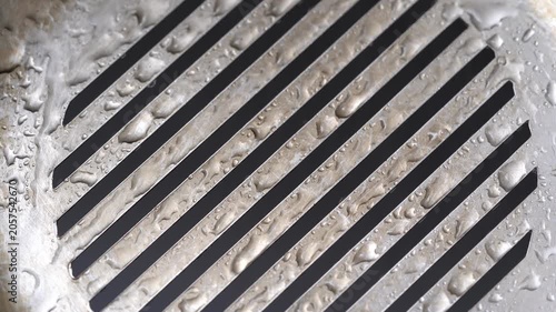 Ultra HD 4K macro video featuring a circular metal grill pattern covered with water droplets. 4K Abstract Metal Grill with Water Droplets – Industrial Texture Macro Video