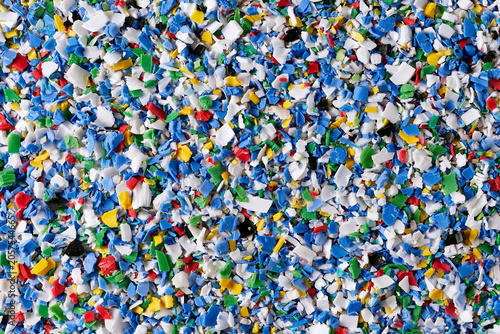 Colorful recycled plastic granules and shredded pieces of PE, ASA, PP, and PA polymers used in manufacturing. Industrial raw material for sustainable production and environmental waste reduction.