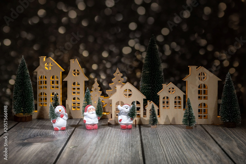 Christmas and New Year cards. Christmas village and toy Santa Claus and snowman on a festive background with garlands in bokeh style. A holiday card.