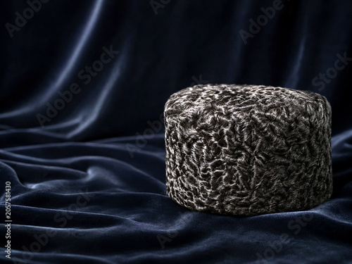 A Karakul fur hat resting on dark velvet, showcasing its texture