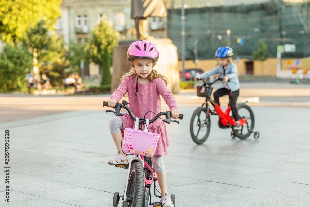 Fototapeta premium Children riding bicycles together wearing safety helmets
