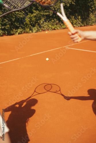 Artistic shadows of tennis rackets cast across a clay tennis court, creative lifestyle sports composition with warm natural sunlight