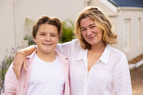 pre teen and young woman siblings smiling and embracing