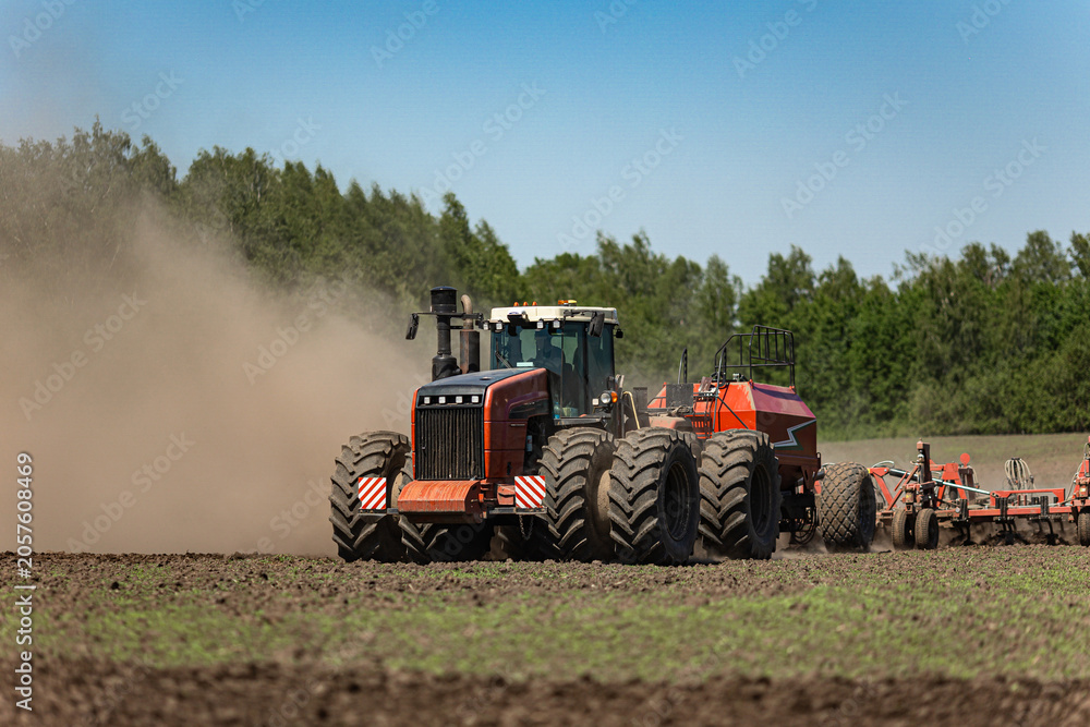 Fototapeta premium Powerful tractor with air seeder working on agricultural field during spring sowing