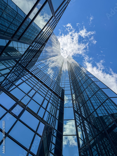 Glass skyscraper reflecting blue sky and clouds.