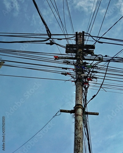 Tangled electrical high voltage power lines on electrical pole in city