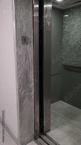 High-quality video of stainless steel elevator doors opening in a clean modern apartment or commercial building corridor. Ideal for illustrating accessibility, transportation, property management, hos