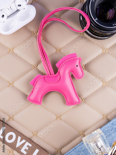 Φωτογραφία Close-up of a leather bag charm with a pink horse, placed on a beautiful table with women's items