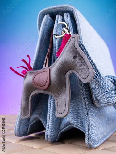 Konstfotografi Close-up of a leather bag charm featuring a gray horse with a pink mane on a blue  bag