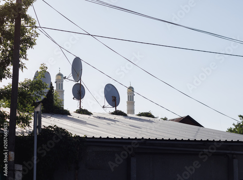 Φωτογραφία old parabolic antennas on the roof against the background of minarets