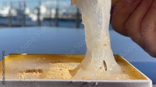 きな粉をトッピングした和菓子のわらび餅。食べたいけど切れず、力強く伸びているわらび餅の動画。