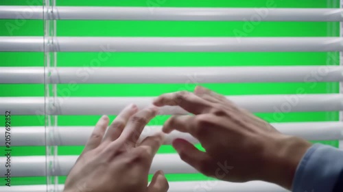 Clean, professional, gender-neutral hands in business-casual sleeves smoothly manipulate modern white window blinds, revealing a vibrant chroma key green screen with a subtle dolly in. Soft studio