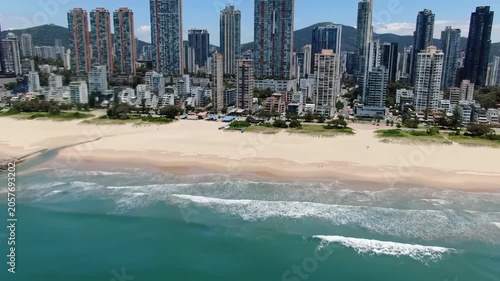 High-altitude aerial drone video of a thriving modern coastal metropolis, with sleek high-rises, bustling traffic, vibrant commercial port, and pristine sandy coastline with clear ocean waves.