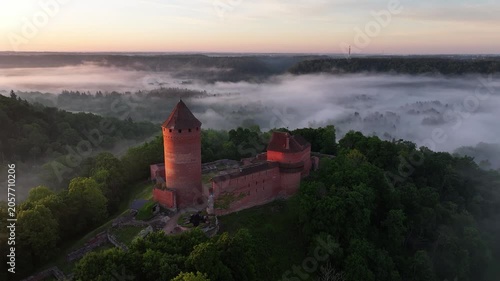 Aerial sunrise view of Turaida Castle rising above morning fog in Gauja National Park, Sigulda, Latvia