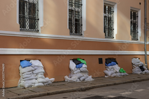 Sandbag barriers protecting urban building during flood emergency with reinforced windows and street defenses. Disaster preparedness resilience public safety and crisis response