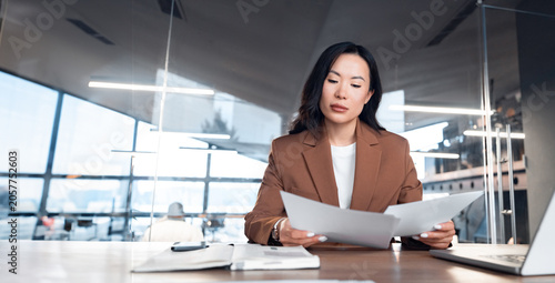 фотографія Professional woman working on laptop at desk in office, reading sale financial contract document papers