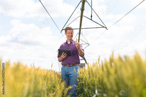Farmer using tablet in wheat field with irrigation system