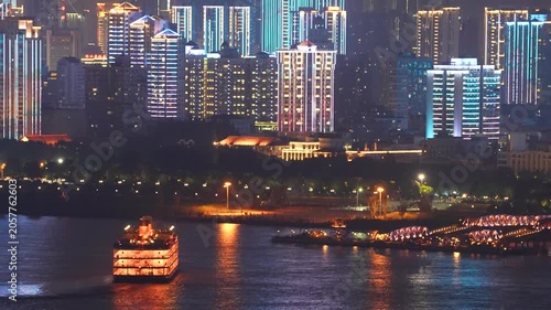 Illuminated riverside city skyline with cruise boat at night