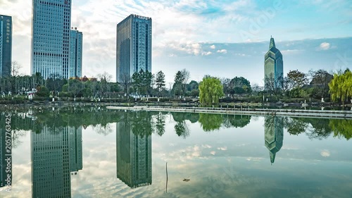 Modern city skyline reflected in calm lake by urban park