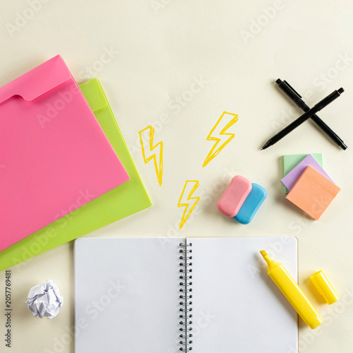 Notebook lies open on a clean desk next to vibrant folders and office supplies featuring bright lightning designs.
