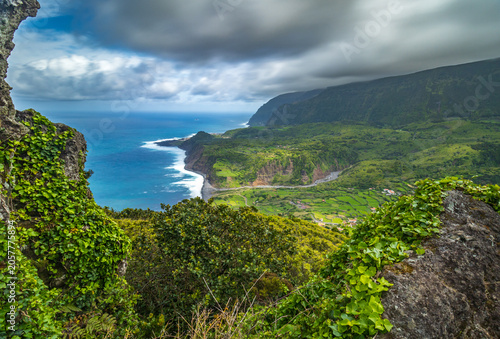 Foto Impresionante vista panorámica de acantilados verdes que caen hacia el océano Atlántico azul, bajo un cielo de nubes dramáticas en la paradisíaca isla de Flores