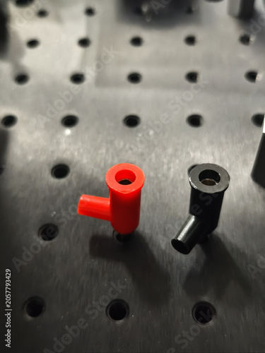 Red and black metal parts on perforated surface, abstract industrial close up with blurred background