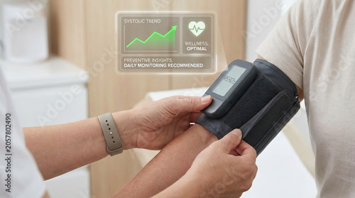 Blood pressure monitor cuff on arm with digital display showing systolic trend and wellness status, hands adjusting cuff for accurate health measurement and daily monitoring
