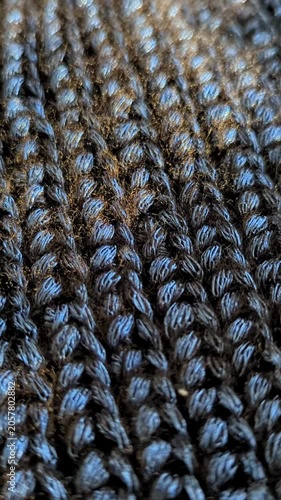 Detailed view of cozy, hand-knitted fabric in shiny dark blue color. Soft, tactile pattern handmade textile for winter close-up