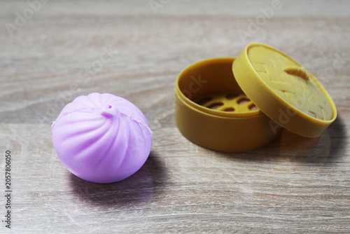 Anti-stress toy in the shape of a pink dumpling squishy lying near the box