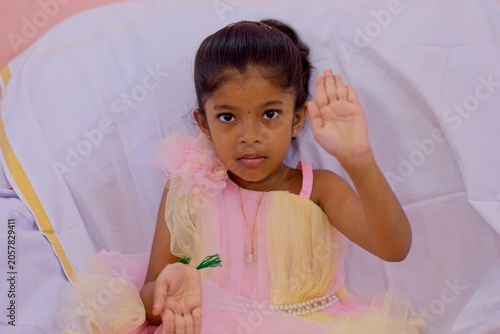 Girl sitting with raised hands in a colorful dress
