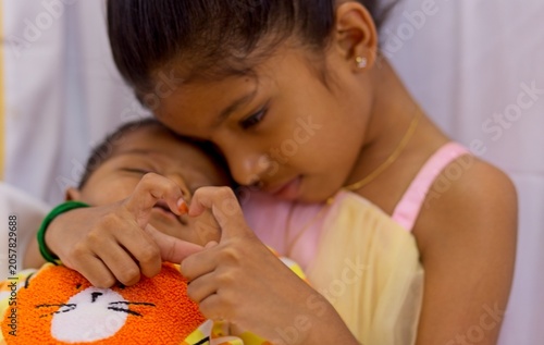 Sibling bond shown through heart gesture and tender embrace at home