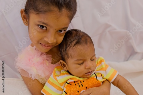 Sister holding her baby brother in a cozy setting