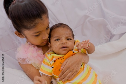 Sister holds baby brother in a cozy setting