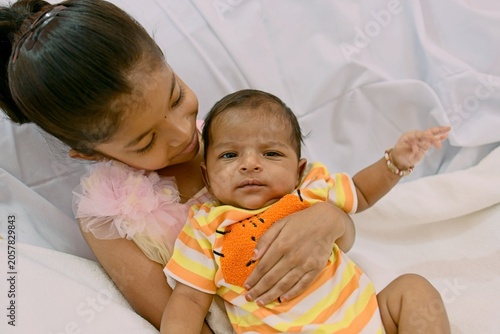Sister holding baby brother with smile and joy in home setting